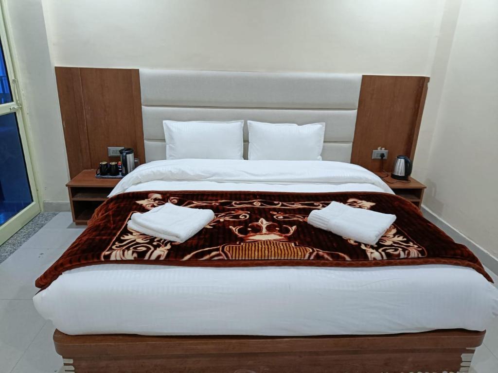 a bedroom with a large bed with two pillows at Shree Kuber Regency in Badrinath