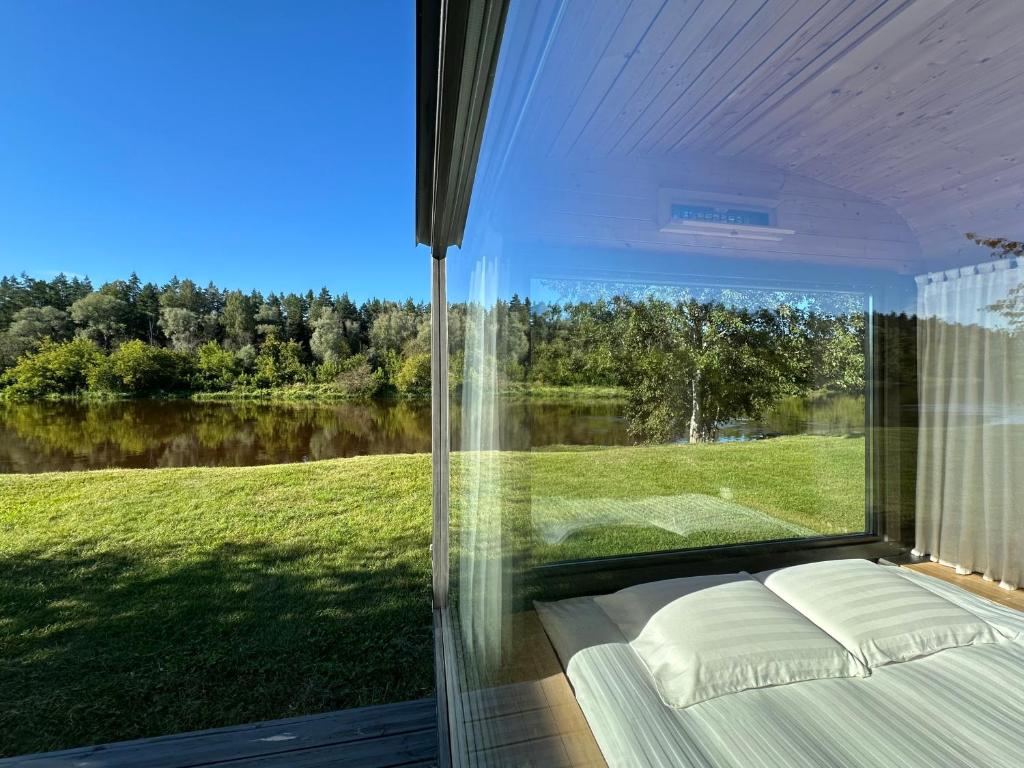 a bedroom with a large window looking out at a river at Citi Krasti Eco Spa Residence in Kārļzemnieki
