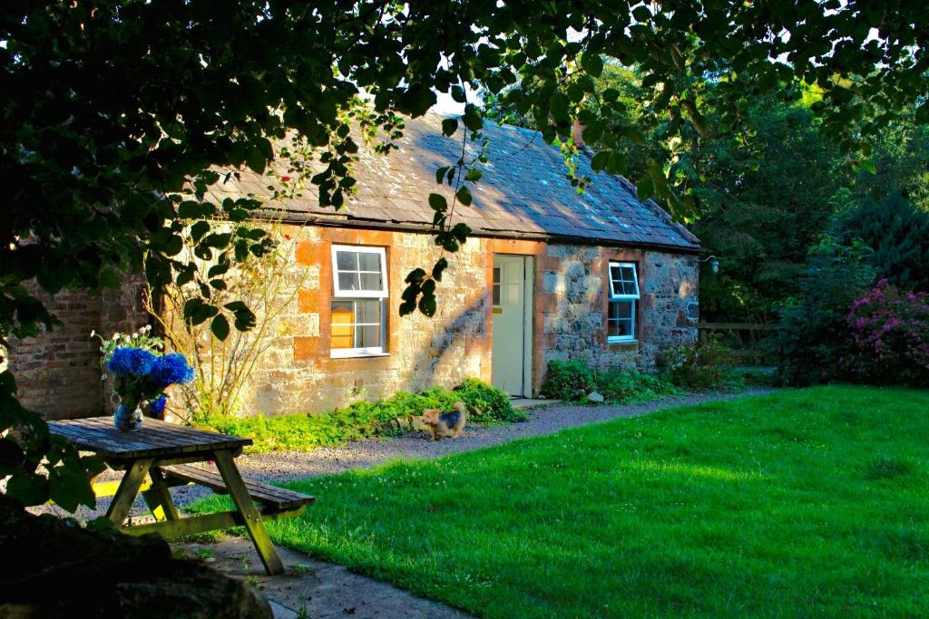 a small stone house with a table in front of it at Little Dunbar in Dumfries