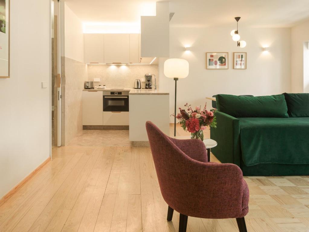 a living room with a green couch and a kitchen at LSA Príncipe Real by Numa in Lisbon