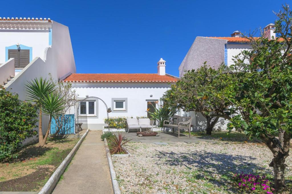 a white house with a yard with trees at Casa Bettina in Vila Nova de Milfontes