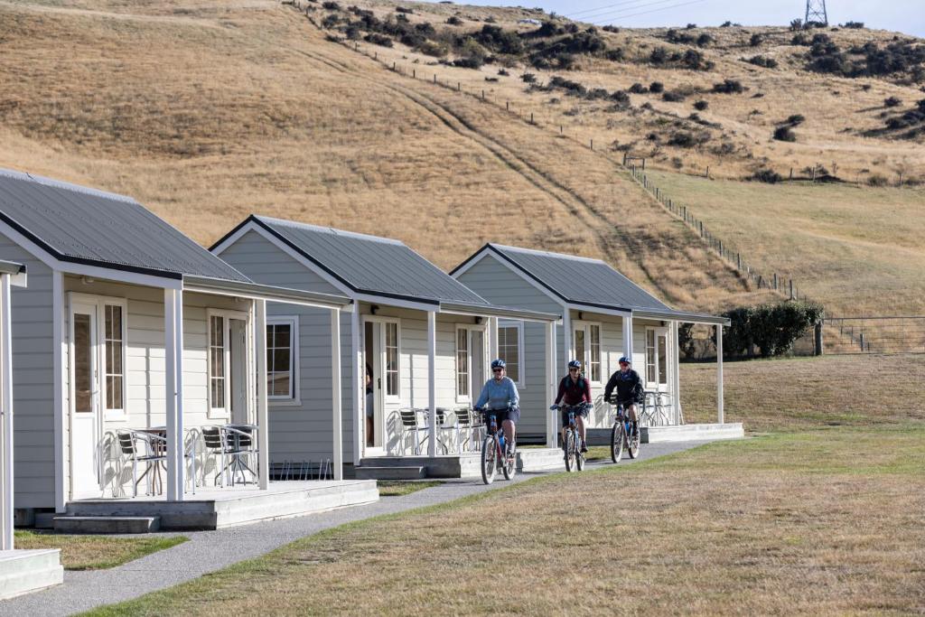three people riding bikes in front of a row of houses at Wedderburn Cottages in Wedderburn