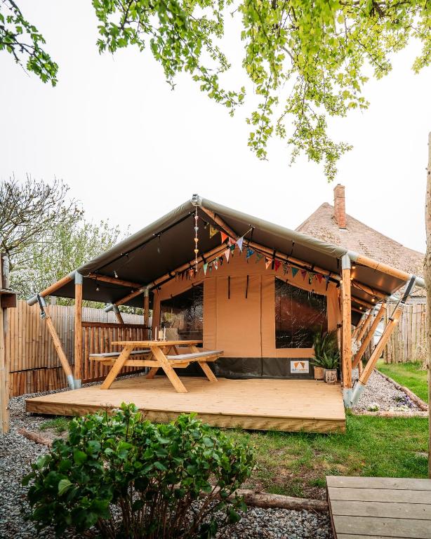 a wooden pavilion with a picnic table in a yard at SoulSafari aan Zee in Julianadorp
