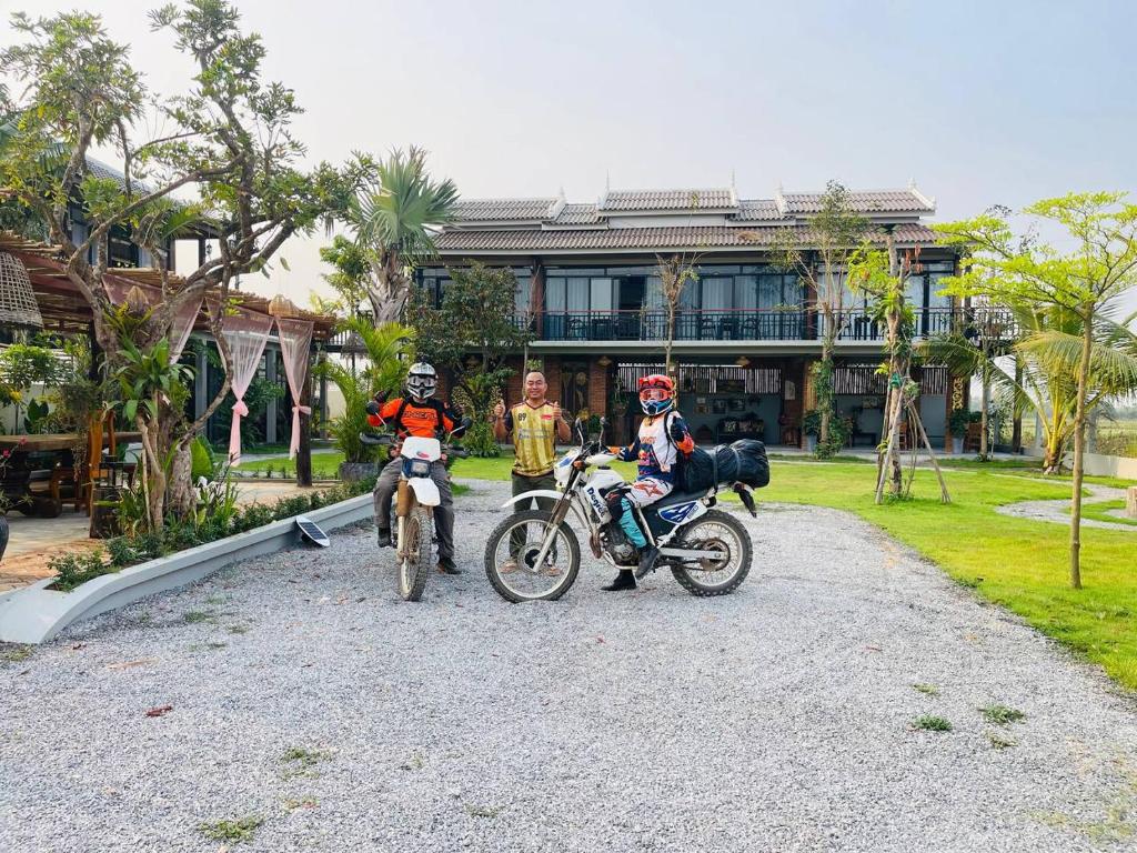 three people on motorcycles parked in front of a building at Sanctuary Homestay Battambang in Phumĭ Don Téav
