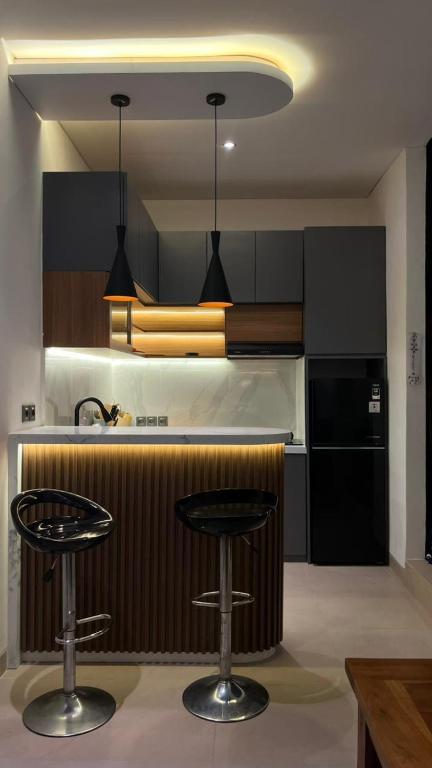 a kitchen with two bar stools and a black refrigerator at Pondok Wahyu in Ubud