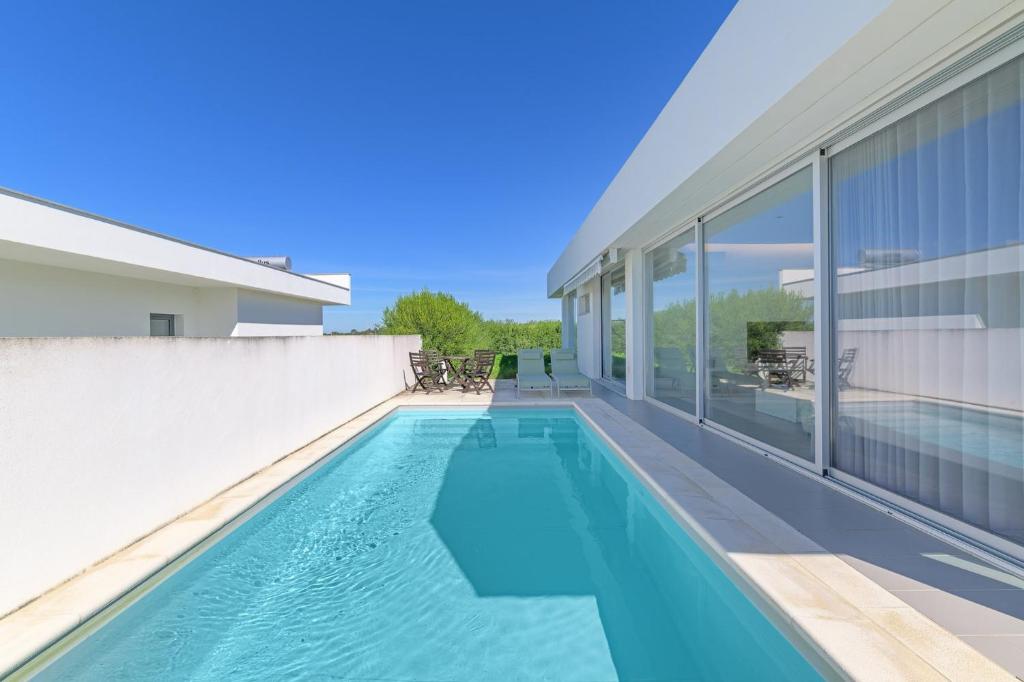 a swimming pool in front of a building at Vila Praia Grande in Sines