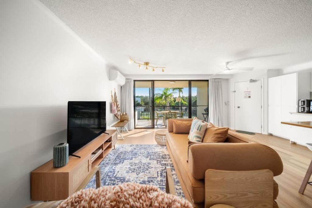 a living room with a couch and a flat screen tv at Coastal Drift - Beach Access Pool Spa Gym in Marcoola