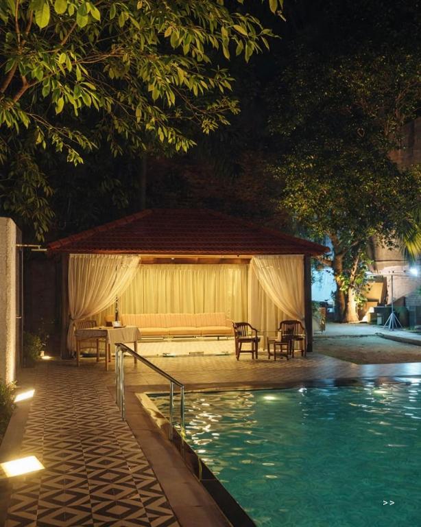 a pavilion next to a swimming pool at night at Amantran Farm Retreat in Varanasi