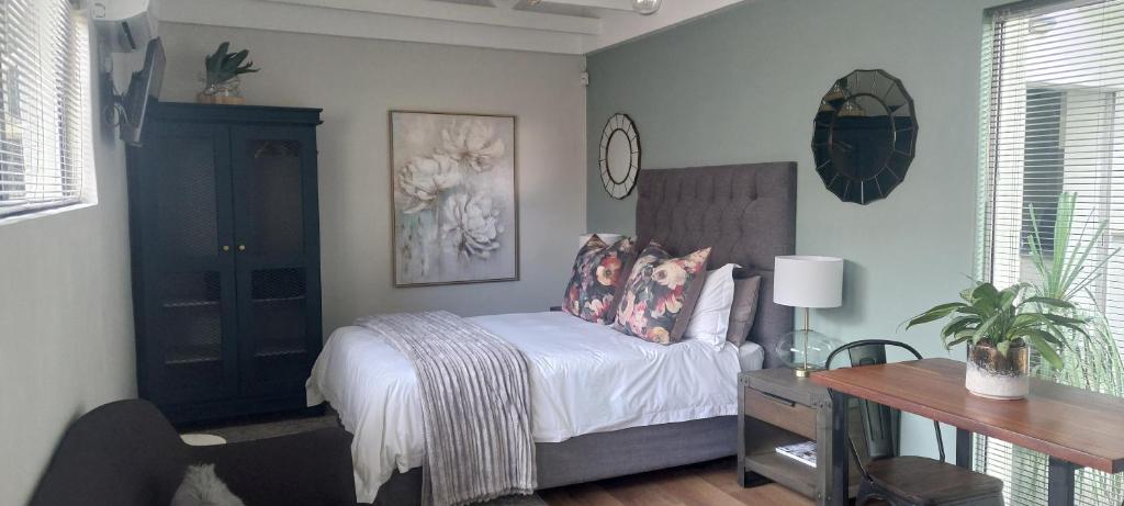 a bedroom with a bed and a table and a desk at Fevertree cottage in Bloemfontein