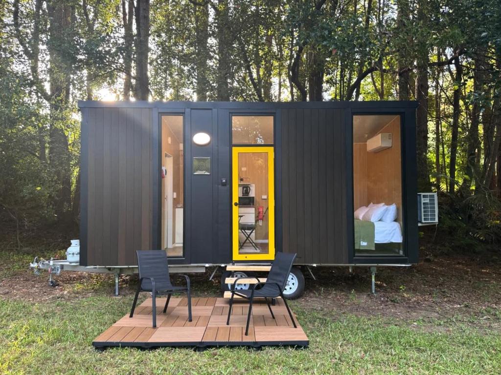 a black tiny house with two chairs and a bed at The Secret Place by Tiny Away in Palmvale