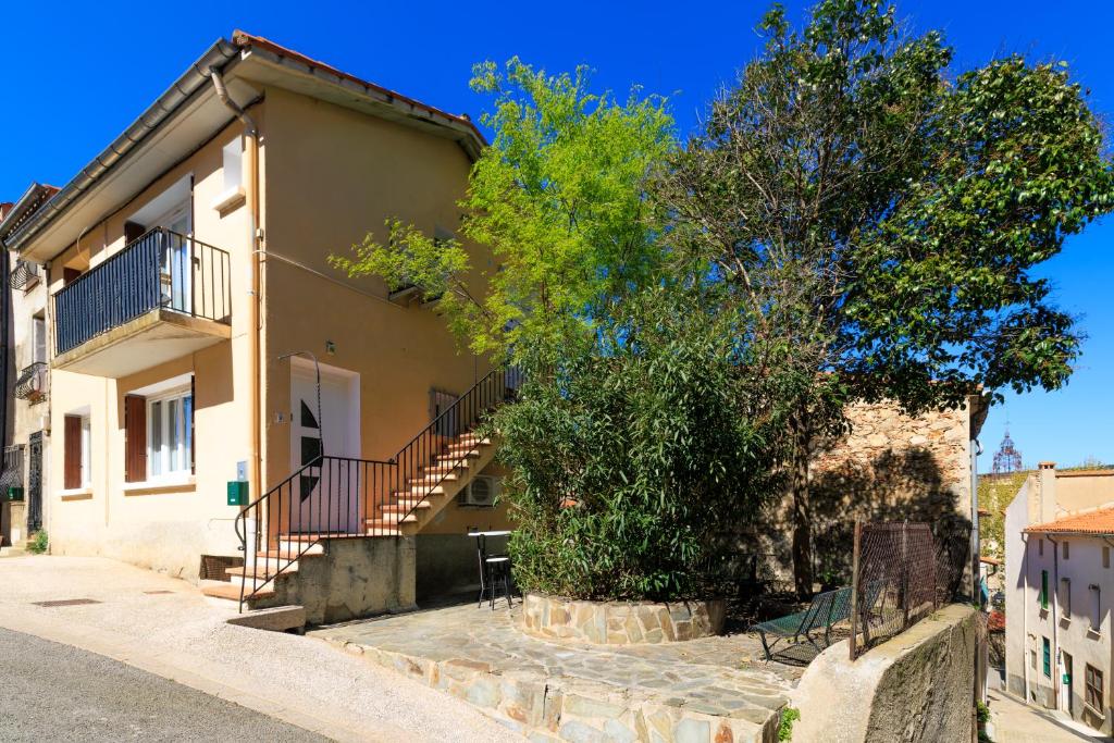 a house with stairs and a tree in front of it at Appart cathare et l'olivier in Tautavel