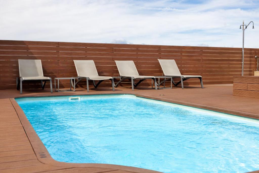 a swimming pool with chairs and a table on a deck at Hotel SB Ciutat Tarragona in Tarragona