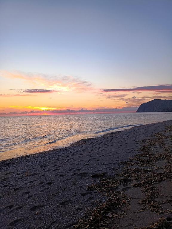 ein Strand mit Sonnenuntergang im Hintergrund in der Unterkunft Lissia Hotel in Skala Eresou