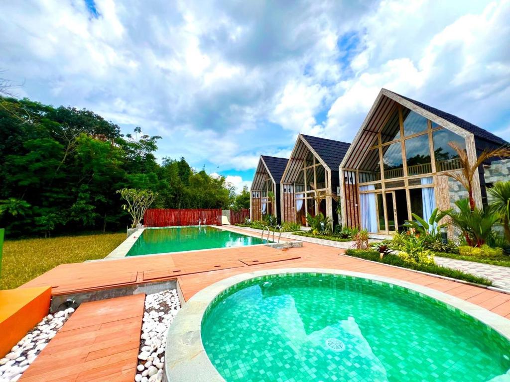 a house with a swimming pool in front of a house at Nglaras Resort Yogyakarta in Ngaglik