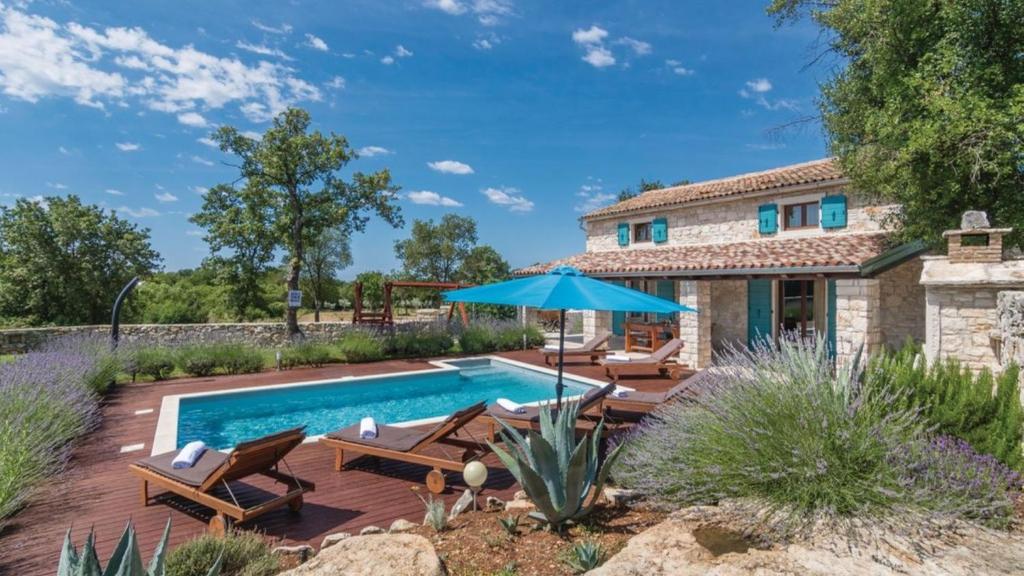 a pool with chairs and an umbrella next to a house at Villa Sabrane by Villas Guide in Bale