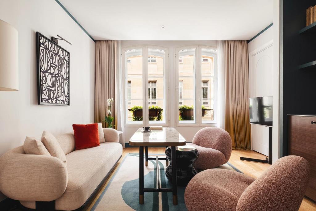 a living room with a couch and chairs and a table at Hôtel Bel Ami in Paris