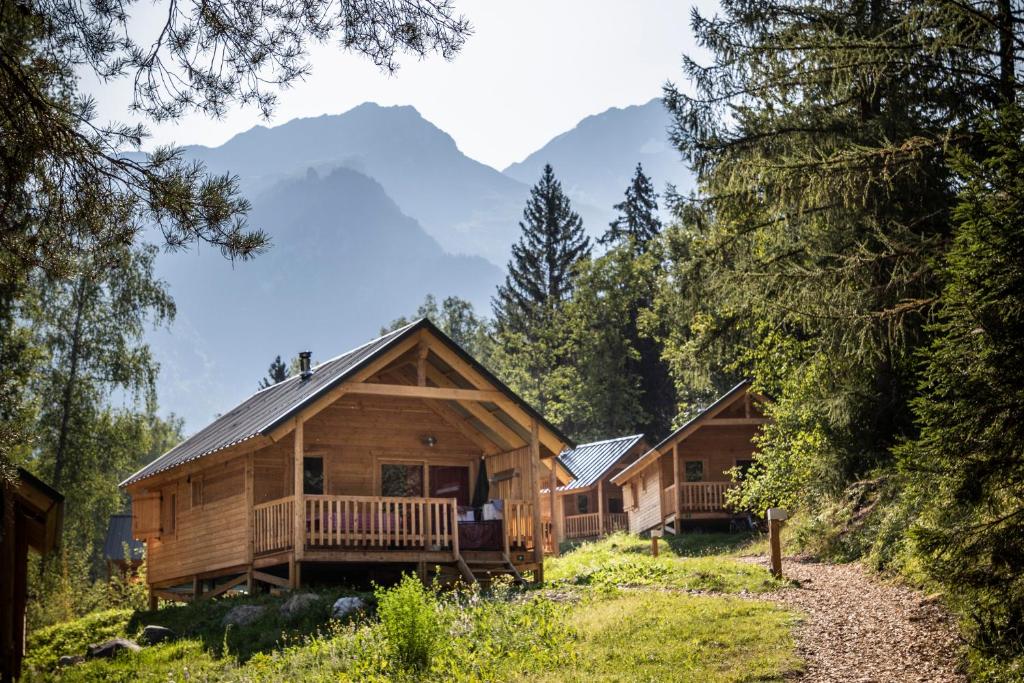 a cabin in the woods with mountains in the background at Huttopia Bozel en Vanoise in Bozel
