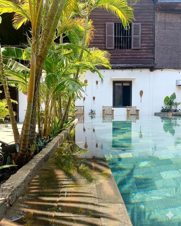 a swimming pool in front of a house with palm trees at La Fontaine de Tara Boutique Hotel in Siem Reap