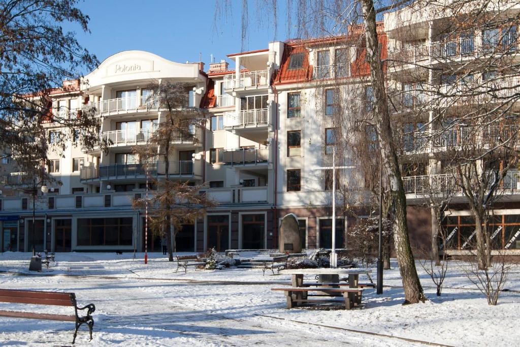 a building in the snow with benches in front of it at Apartament Polonia in Ełk