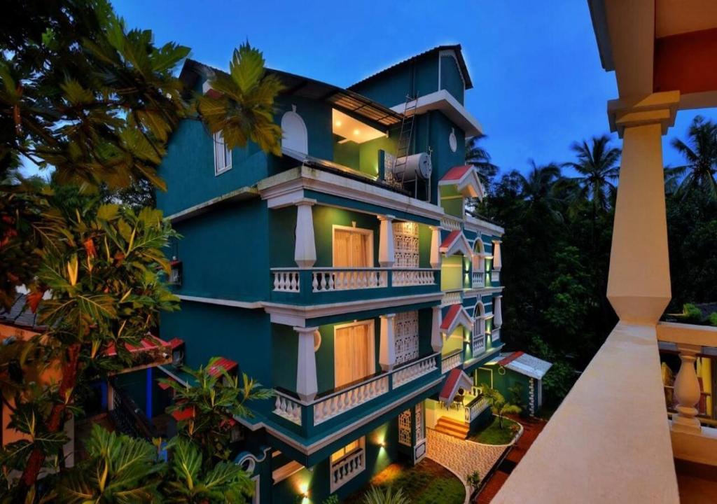 ein blaues Gebäude mit Balkonen und Palmen in der Unterkunft TreeHouse Nova in Cansaulim