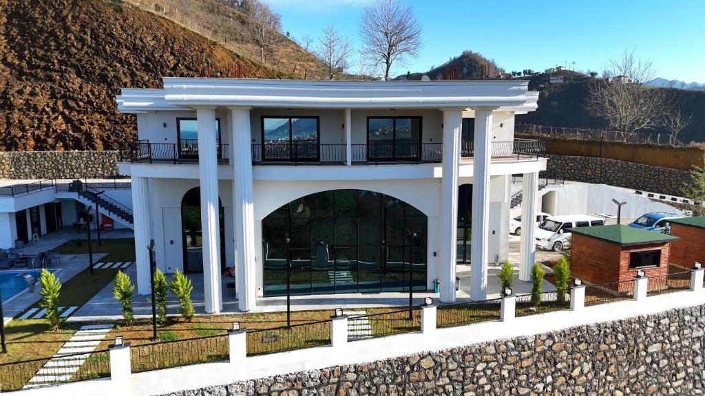 a large white house with a balcony on a hill at Gelevera Park - Otel Spa Restaurant in Espiye