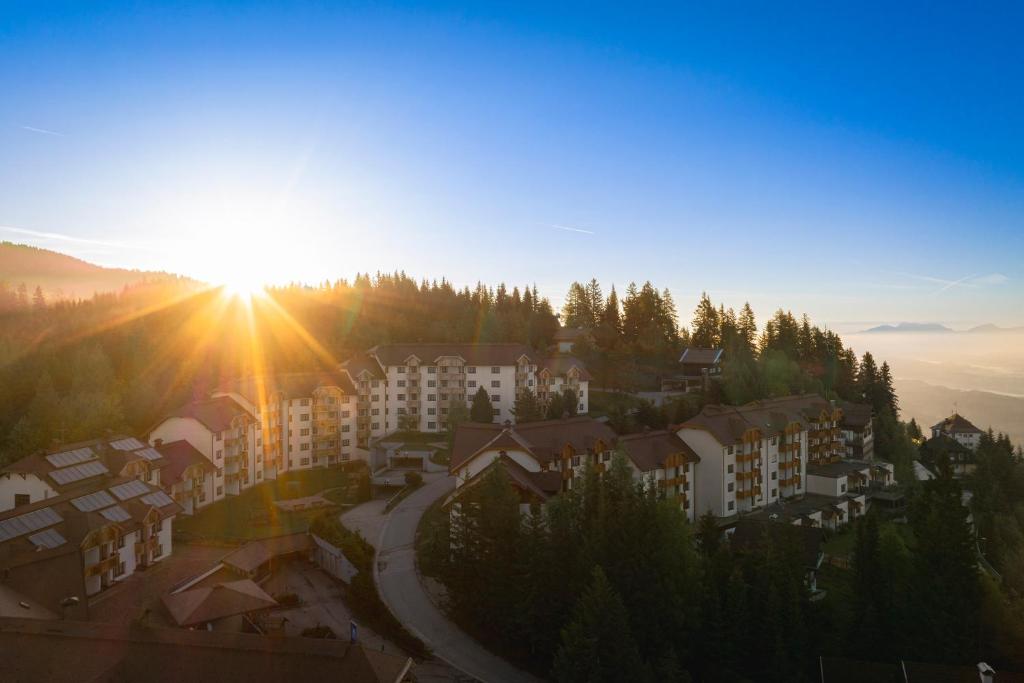 a view of a city with the sun setting at Bergresort Gerlitzen in Treffen