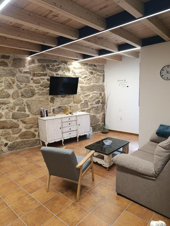 ein Wohnzimmer mit einem Sofa und einem Fernseher an einer Steinwand in der Unterkunft Trisquel 2 in Laroá
