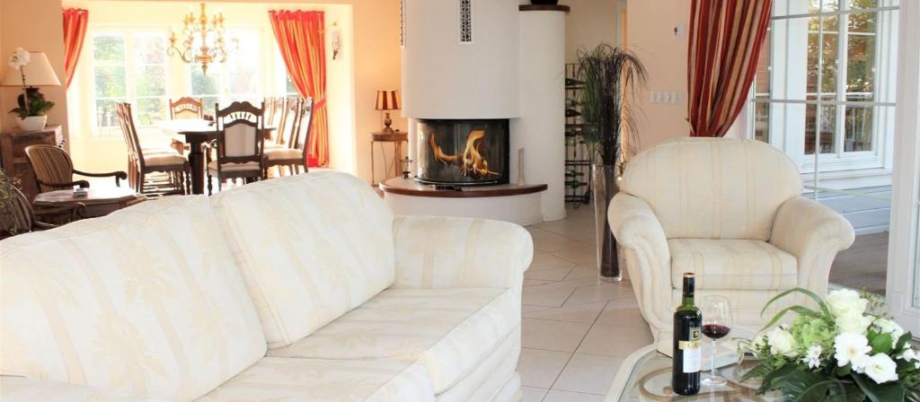 a living room with two white couches and a fireplace at Ferienvilla Recknitztal in Marlow