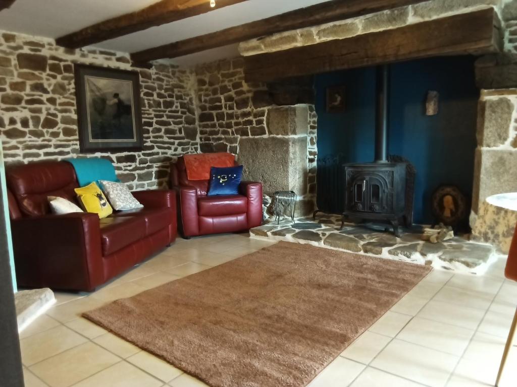 a living room with two chairs and a fireplace at The Old Cider Press in Carnoët