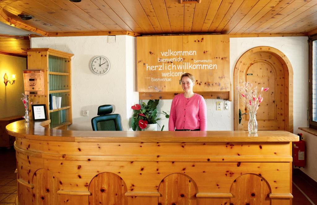 a woman standing behind a wooden counter in a room at La Collina Coliving and Coworking in Grächen