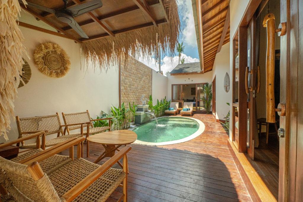 an indoor patio with a pool and tables and chairs at Gili Nomade Villas in Gili Trawangan