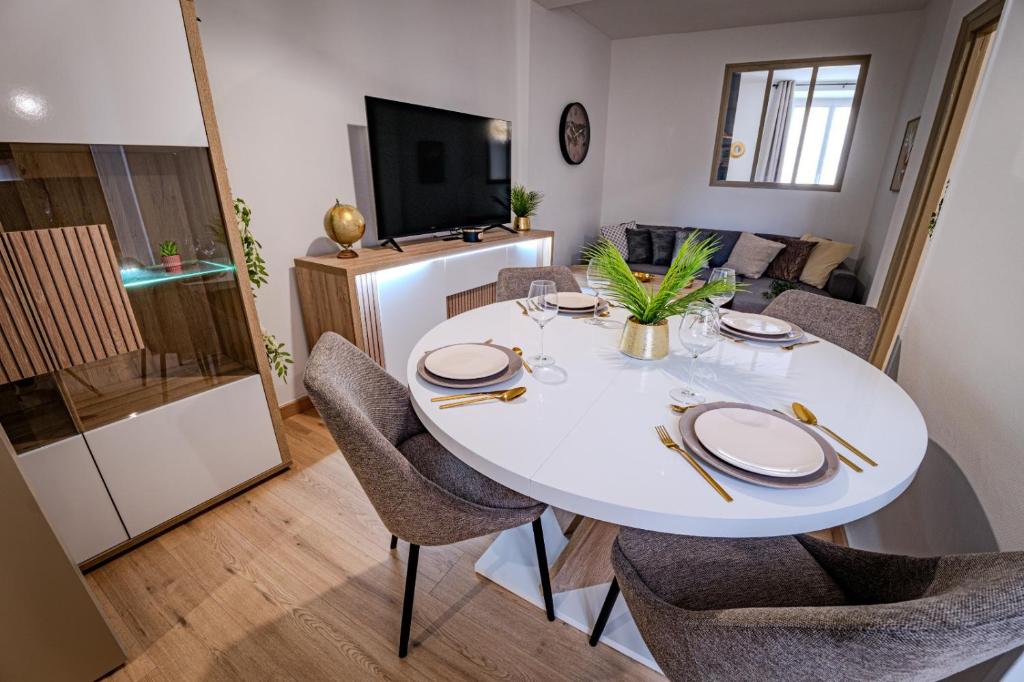 a dining room with a white table and chairs at TEMPLE JACQUESSON - Gare - Centre ville - WIFI RAPIDE et STREAMING - PARKING GRATUIT - CHECK IN 24H - CLIMATISATION - IDEAL PROS - cour privée - barbecue in Chalons en Champagne