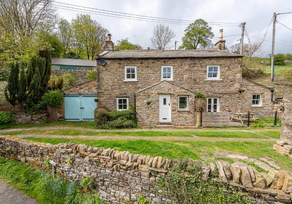 an old stone house with a stone wall at Swale View in Feetham