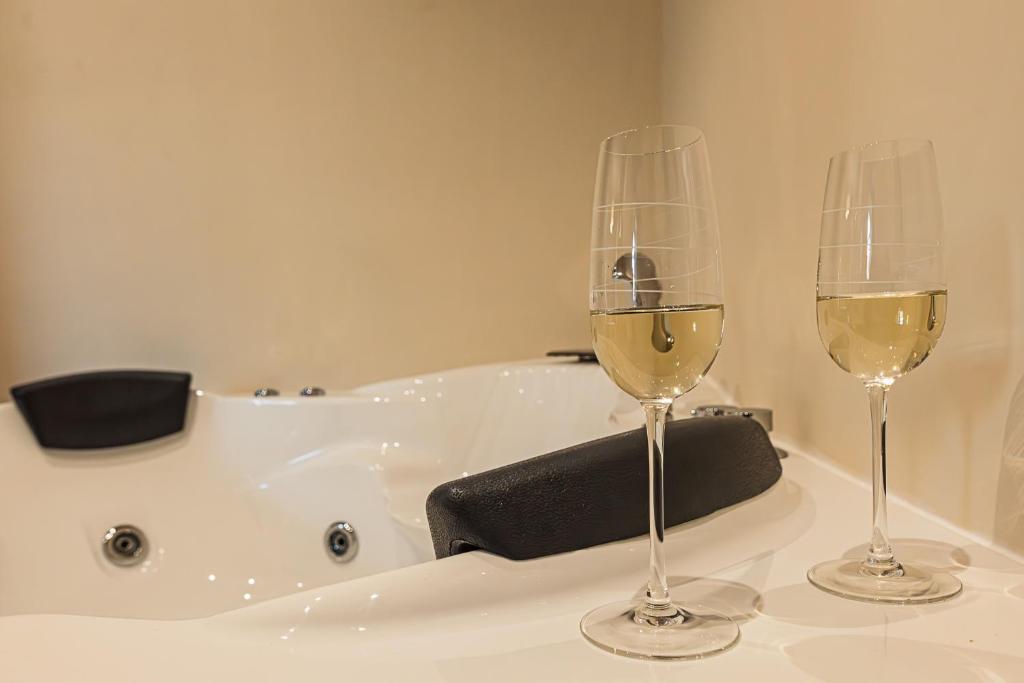 two glasses of white wine sitting next to a bath tub at Villa Decimum in Ciampino