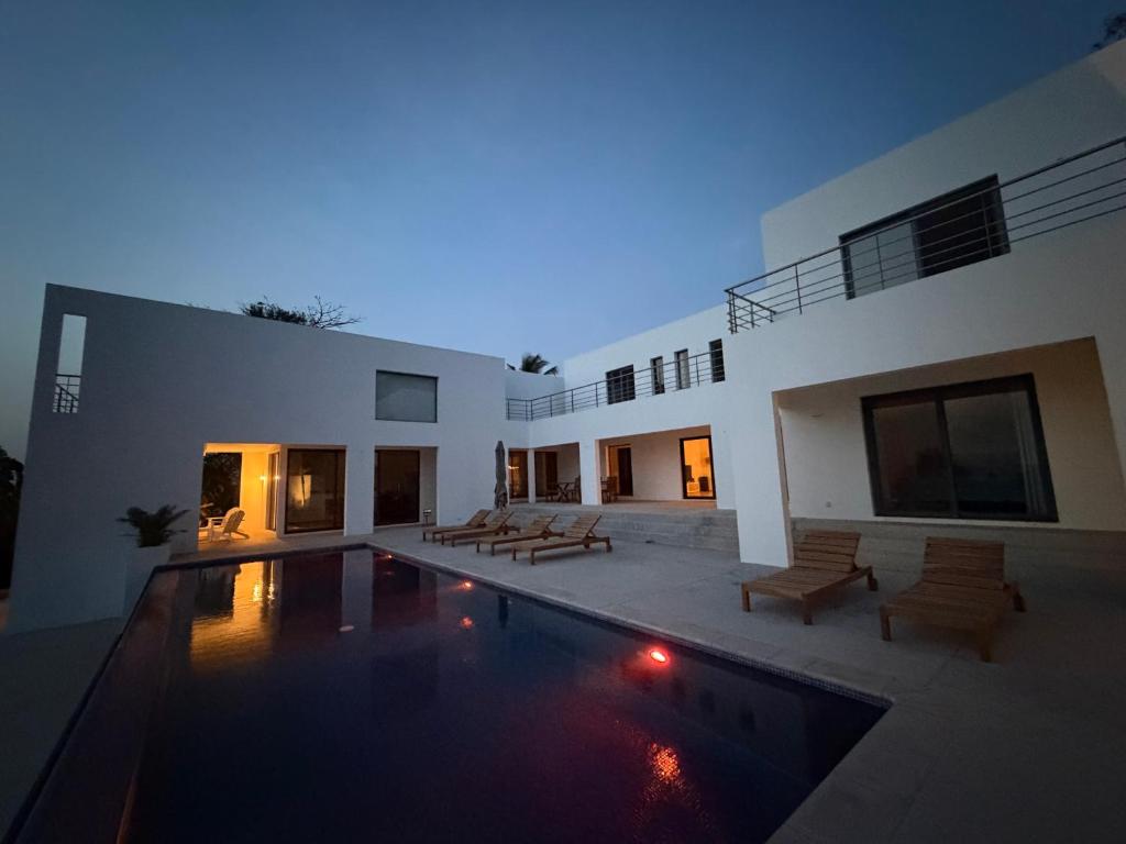 a large house with a swimming pool in front of it at Maison des Alizés in Oussouye
