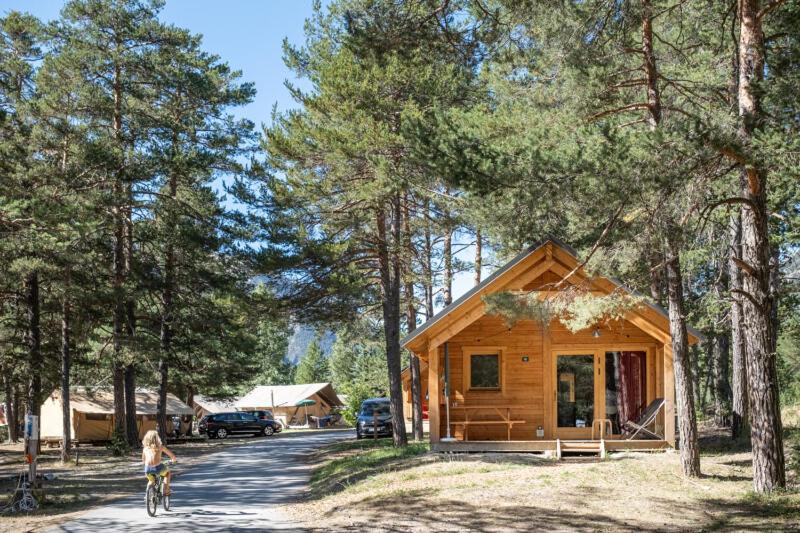 a young girl riding a bike in front of a cabin at Huttopia La Clarée in Val-des-Prés