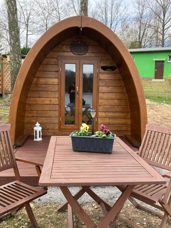 a wooden picnic table in front of a small house at Nr 5 Camping Pod mit Terrasse und Seeblick in Langenbernsdorf