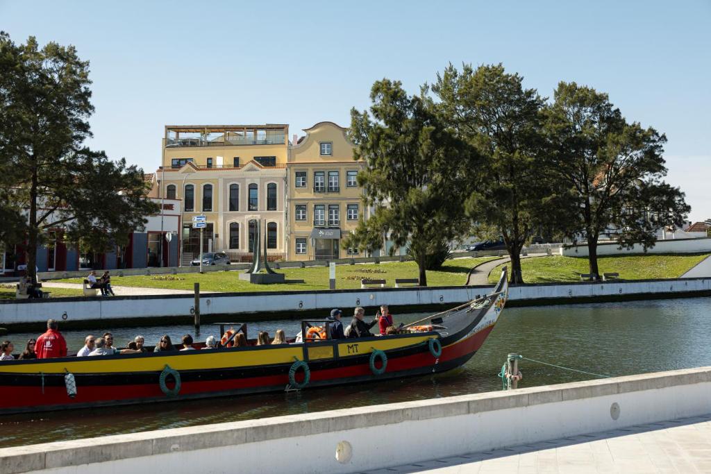 Ein Boot voller Menschen auf dem Wasser vor einem Gebäude in der Unterkunft Hotel do Alboi in Aveiro