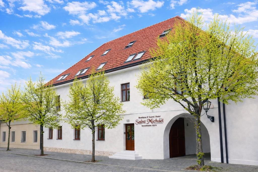 ein weißes Gebäude mit rotem Dach in der Unterkunft Saint Michael Boutique & Garni Hotel Trnava in Trnava