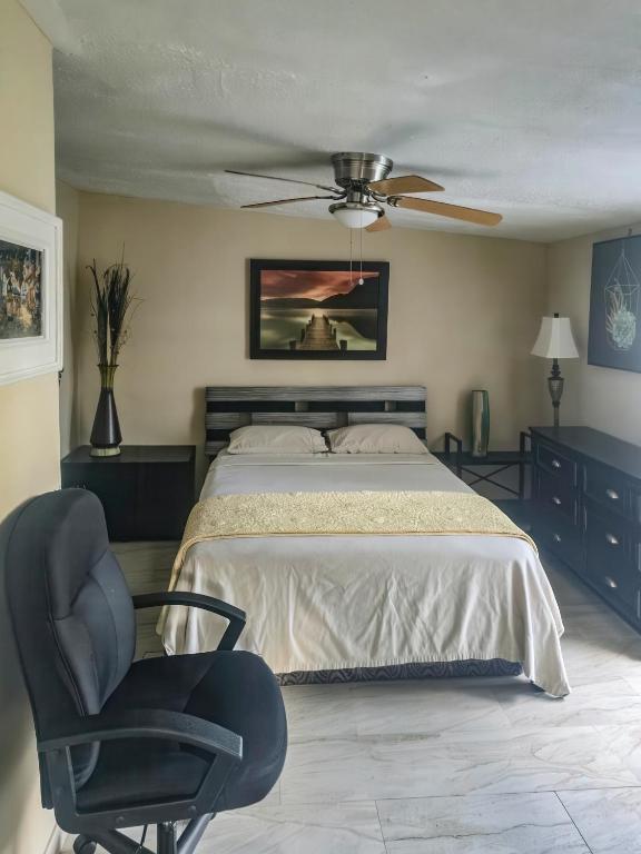 a bedroom with a bed and a chair and a ceiling fan at Studio Efficiency Apartment - a peaceful retreat in Port St Lucie in Port Saint Lucie