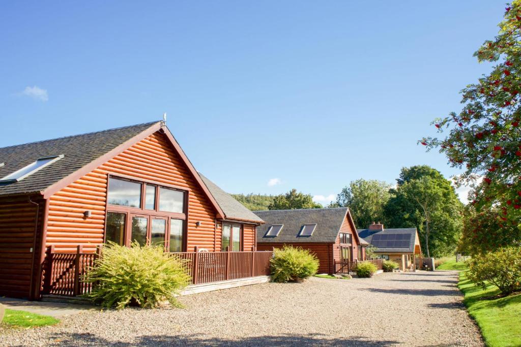 a wooden house with a driveway in front of it at Apple Tree Lodge in Errol