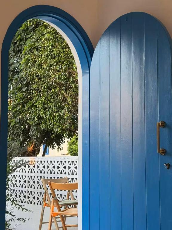 a blue door with a chair in front of a fence at Latchi Holiday House in Prodhromi