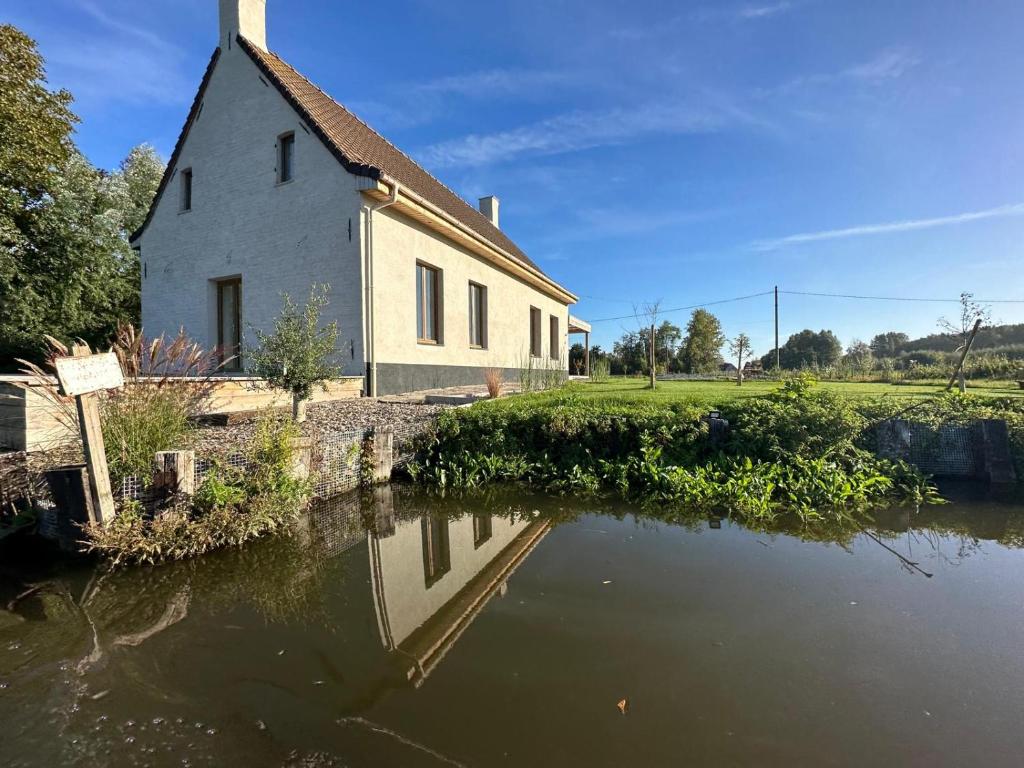 a church with a reflection in a body of water at La Houblonnière Eperlecques Gite d'Ecou in Tilques