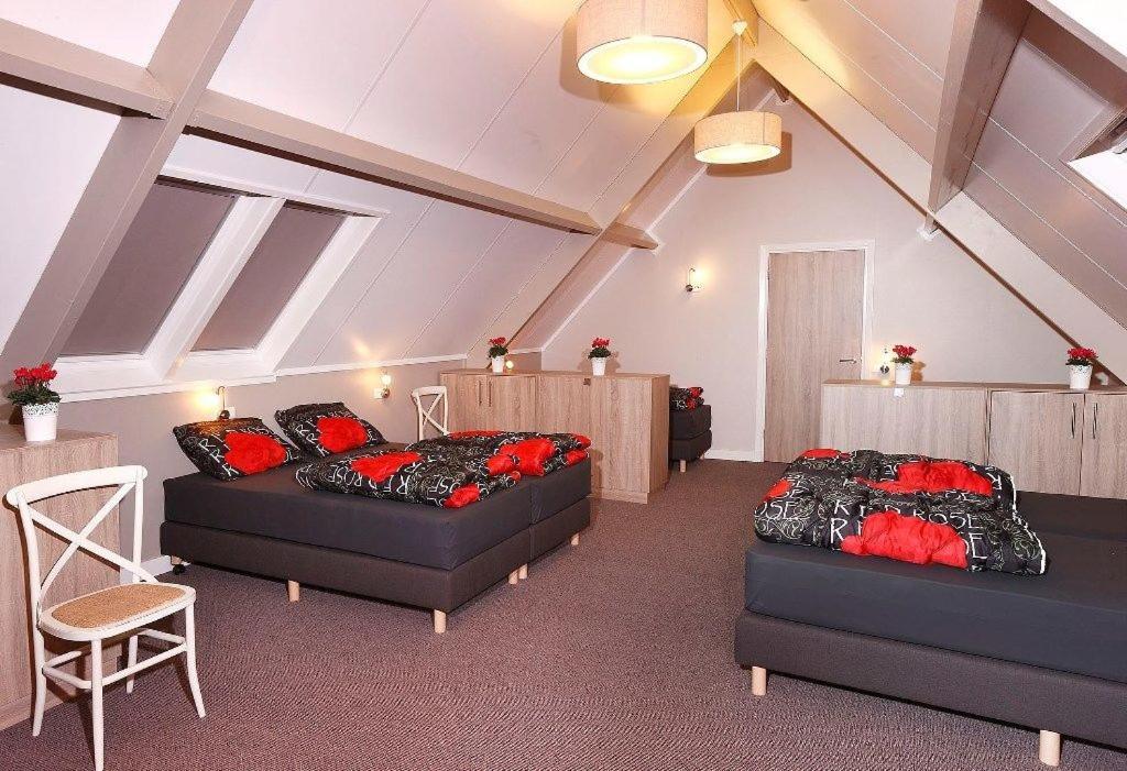 a attic room with two beds and a chair at De Sterre in Losser