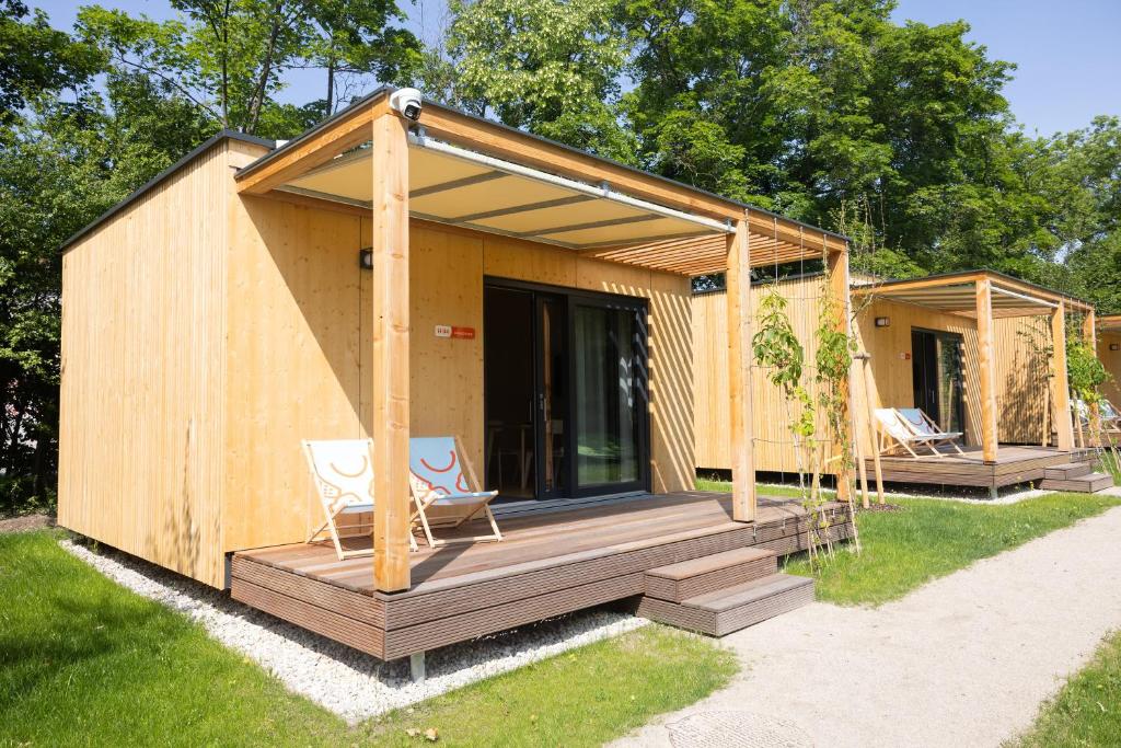 a wooden house with two chairs and a porch at MICAMPA Wien Wienerwald in Vienna