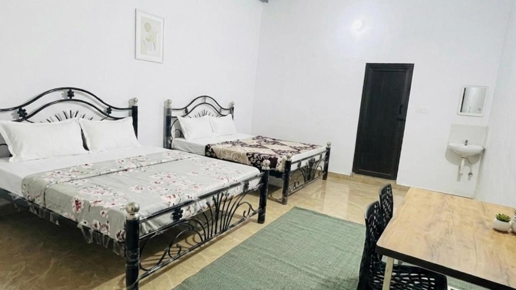 a bedroom with two beds and a table and a sink at StayIn-SGH near Mysore palace in Mysore