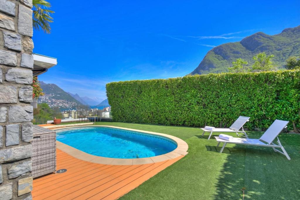 a backyard with a swimming pool and a lawn with two chairs at Lugano Lake View Villa with Private Pool in Lugano