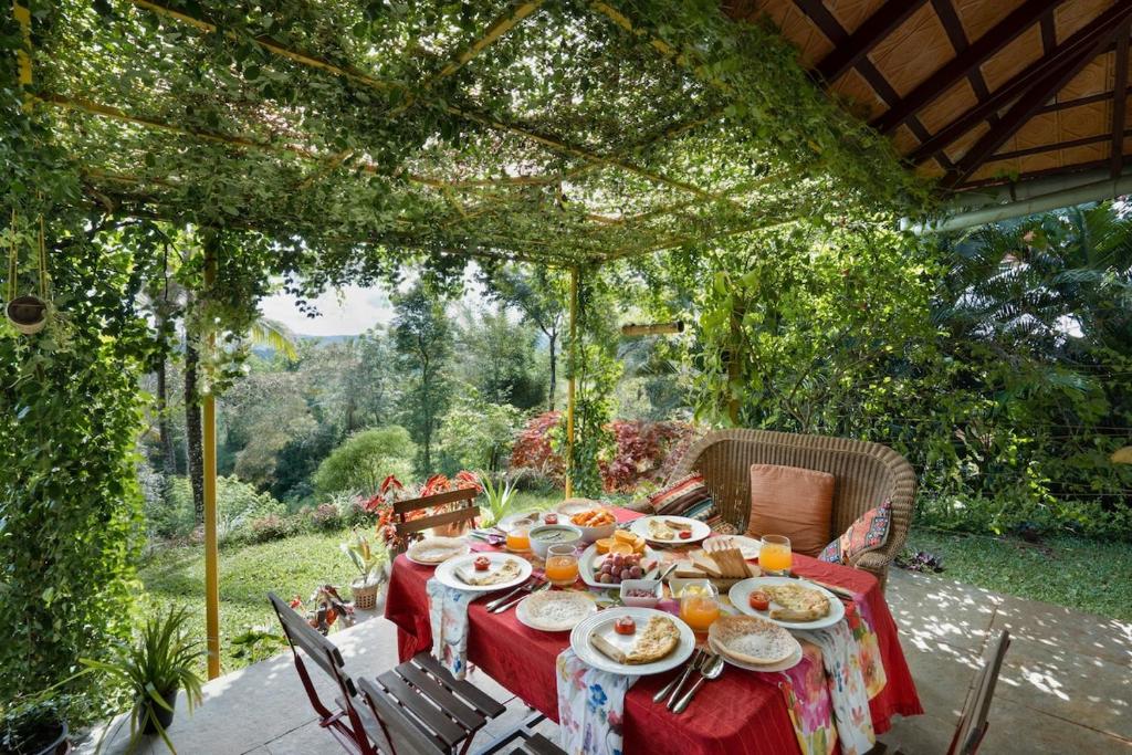 a table with plates of food sitting under a pergola at Deja View - A LuxUnlock Private Villa in Wayanad