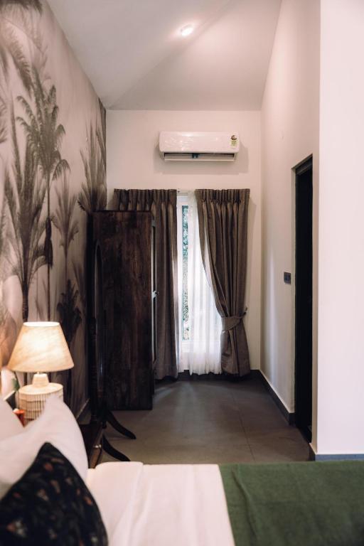 a bedroom with a bed and a window with curtains at Tusker Trails - A LuxUnlock Private Retreat in Suntikoppa