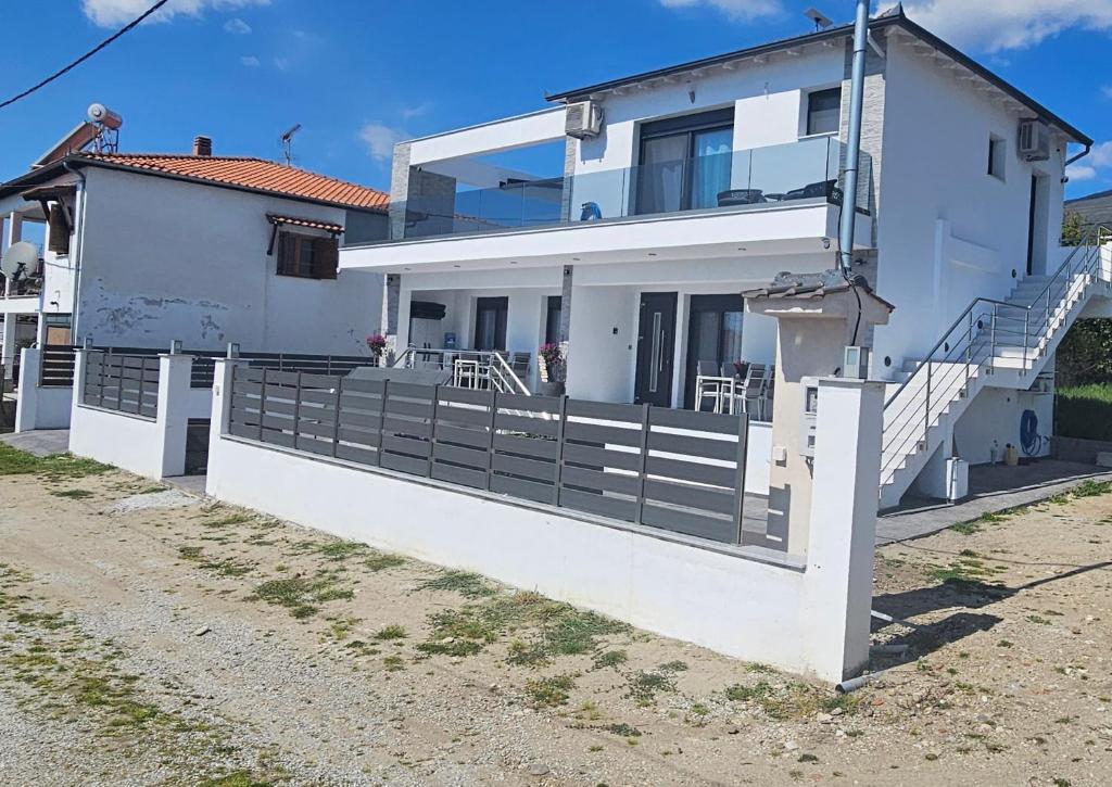 a white house with a white fence and stairs at DaRo-Appartments in Asprovalta